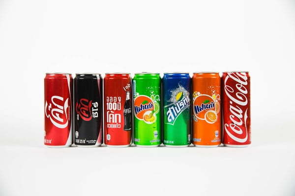 row of cans of pop with their logos obscured - you can still tell what the drink is as the company demonstrates near perfect brand consistency