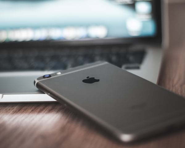 apple iphone and apple macbook on a desk showcasing their logo as an example of brand consistency 