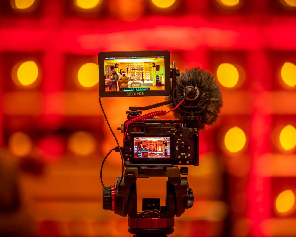 camera and video camera set up to record a marketing video with dramatic red backdrop