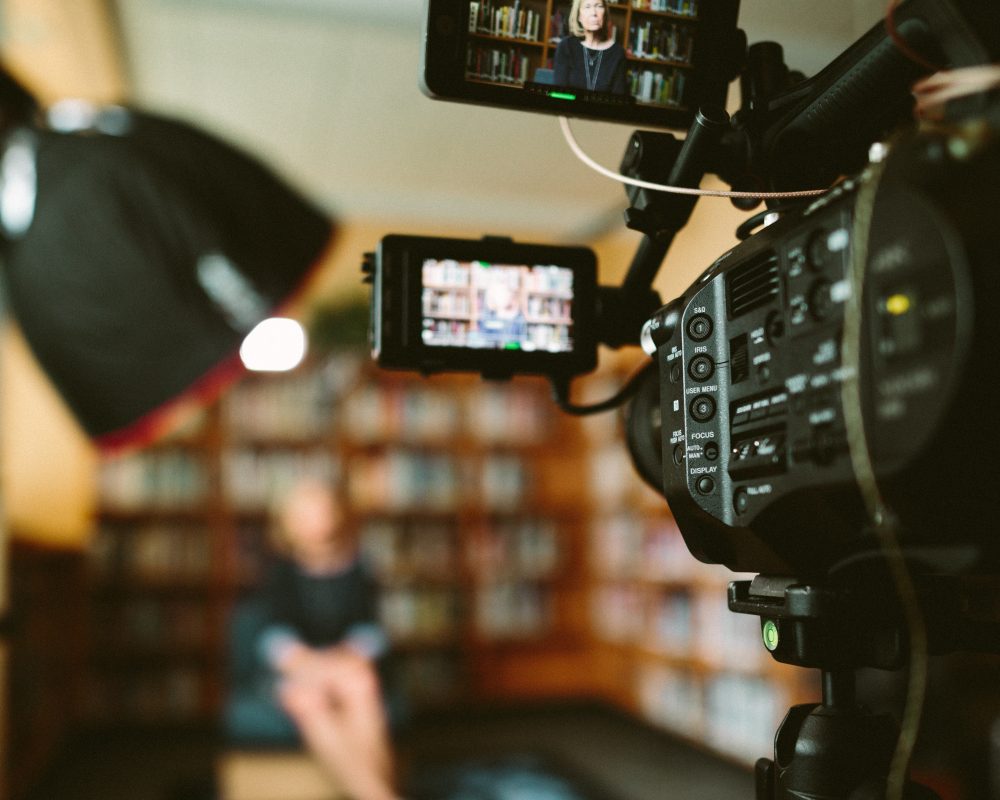 Lady seated in library and camera focussed on her ready to record a marketing video