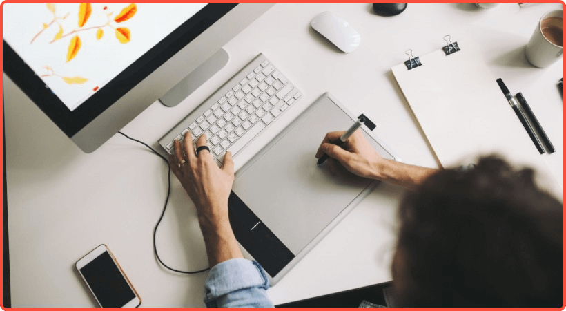 Person designing a webpage using a graphics tablet and desktop computer.
